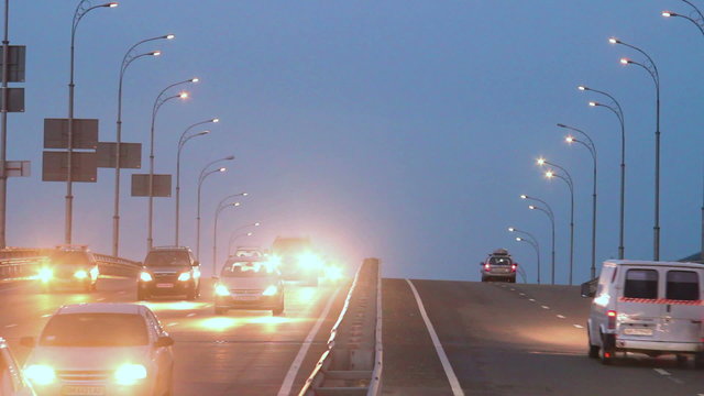 Dense evening traffic, cars drive lights dusk city highway road