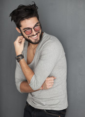 sexy fashion man with beard dressed casual smiling against wall