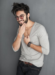 sexy fashion man with beard dressed casual smiling against wall