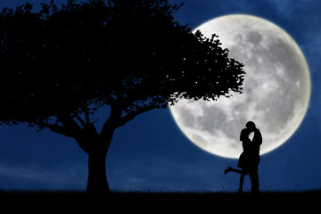 Couple kissing by a tree on blue full moon silhouette