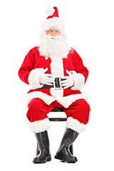 Happy Santa claus sitting on a wooden chair