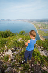 Naklejka premium Boy hiker looking down from the top of the mountain.
