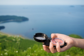 Boy hand holding a compass on the background of a seascape