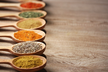 Assortment of spices in wooden spoons on wooden background