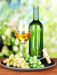 Wine bottle and glass of wine on tray, on bright background