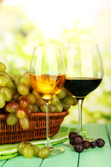 Ripe grapes in wicker basket, and  two glasses of wine,