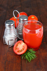 Tomato juice in glass, on wooden background
