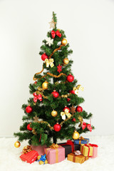 Obraz na płótnie Canvas Decorated Christmas tree with gifts on grey wall background