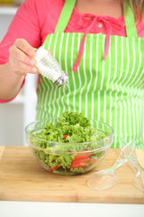 Happy smiling woman in kitchen preparing vegetable salad