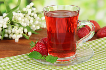 Delicious strawberry tea on table on bright background