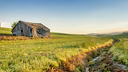 Farm field drainage and barn at sunrise