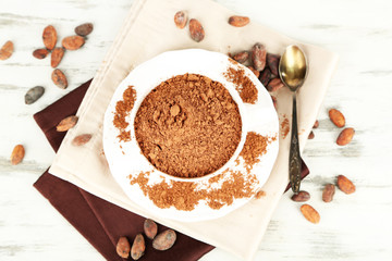 Cocoa powder in cup on napkin on wooden table