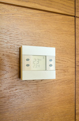 Digital thermostat panel on wooden wall