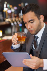 Serious businessman working on his tablet computer while having