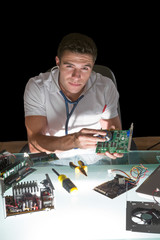 Smiling computer engineer examining hardware with stethoscope by