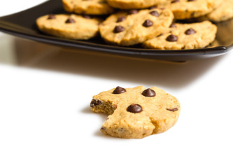 Chocolate chip cookie with a bite and pile of cookies in a plate