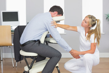 Obraz premium Masseuse treating clients arm in massage chair