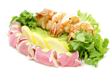 shrimp and tuna with greens and sauce on a white background