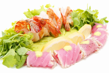 shrimp and tuna with greens and sauce on a white background