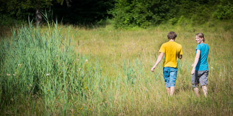romantic twosome young couple walking through high grass