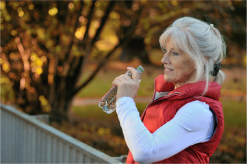 Sportliche Seniorin erfrischt sich mit Mineralwasser
