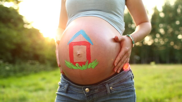 Baby belly in sunlight with house painted on it