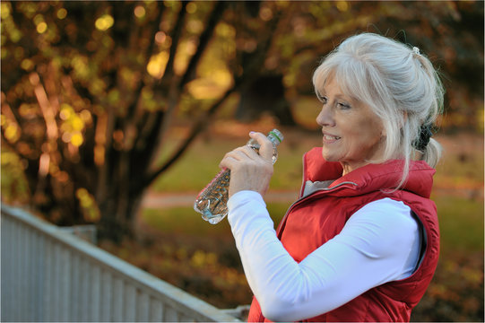Sportliche Seniorin erfrischt sich mit Mineralwasser