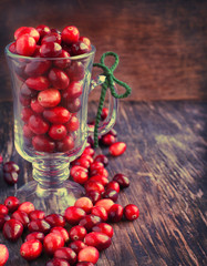 Ripe cranberries in glass cup on wooden background