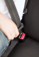 man fastening seat belt in car
