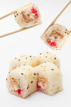 Sushi roll in mamenori with red tobiko in chopsticks