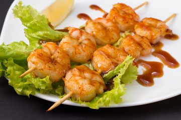 Fototapeta premium Shrimp shashlik on white plate with sauce and salad