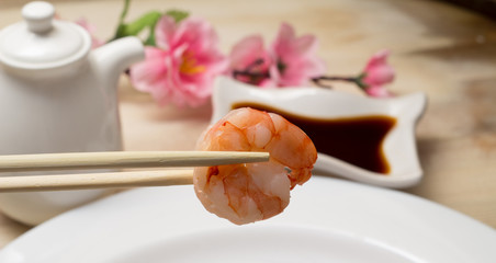 Fried shrimp wirh soy sauce in chopsticks