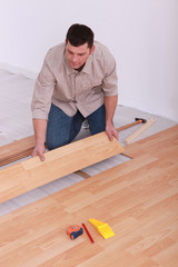 Labourer slotting together laminate flooring