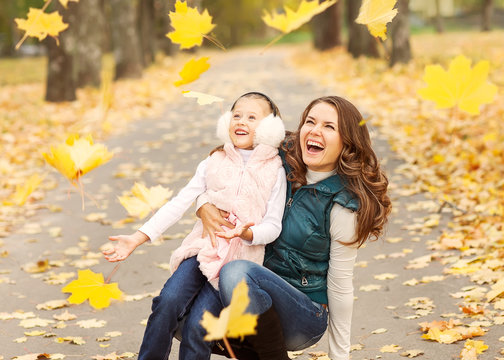 Mother and daughter having fun in the autumn park 