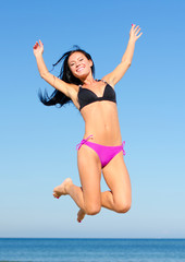 Happy woman jumping in the water at the beach