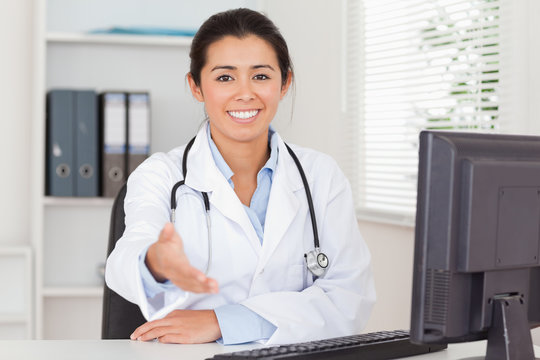 Pretty female doctor inviting somebody to seat while looking at