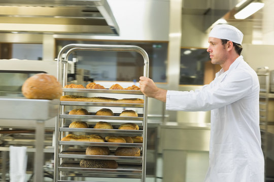 Young Male Baker Pushing A Trolley