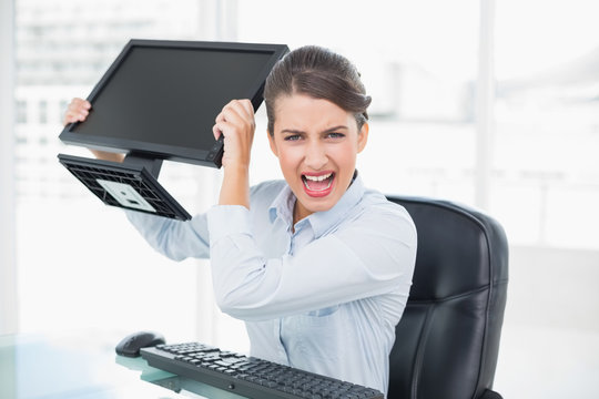 Annoyed classy brown haired businesswoman throwing her computer