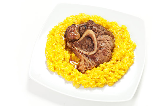 riso allo zafferano con ossobuco di bovino su sfondo bianco
