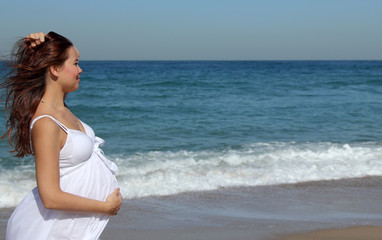 Fototapeta na wymiar beautiful pregnant woman standing on the beach