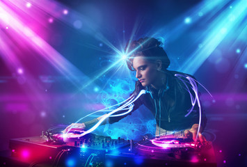 Energetic Dj girl mixing music with powerful light effects