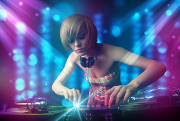 Dj girl mixing music in a club with blue and purple lights