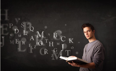 Young man reading a book with alphabet letters