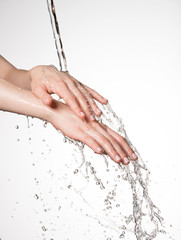 Closeup female hands under the stream of splashing water