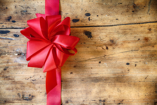 Decorative red bow on rustic wood background