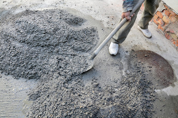 Hand mixing concrete worker with shovel at construction site