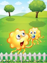 A hilltop with an orange monster playing with a baby monster