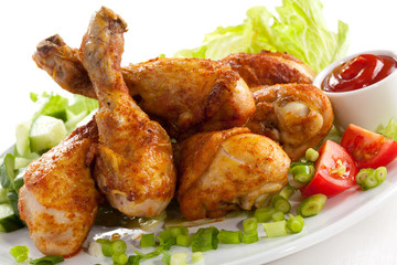 Grilled chicken legs and vegetables on white background