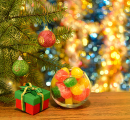 Gift and bowl with candies on blurred background