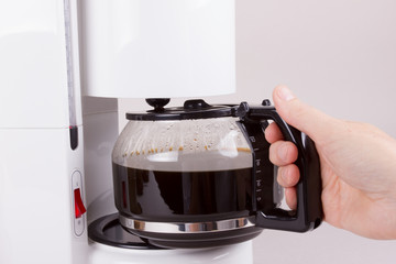 Kaffeekanne aus Kaffeeautomat nehmend